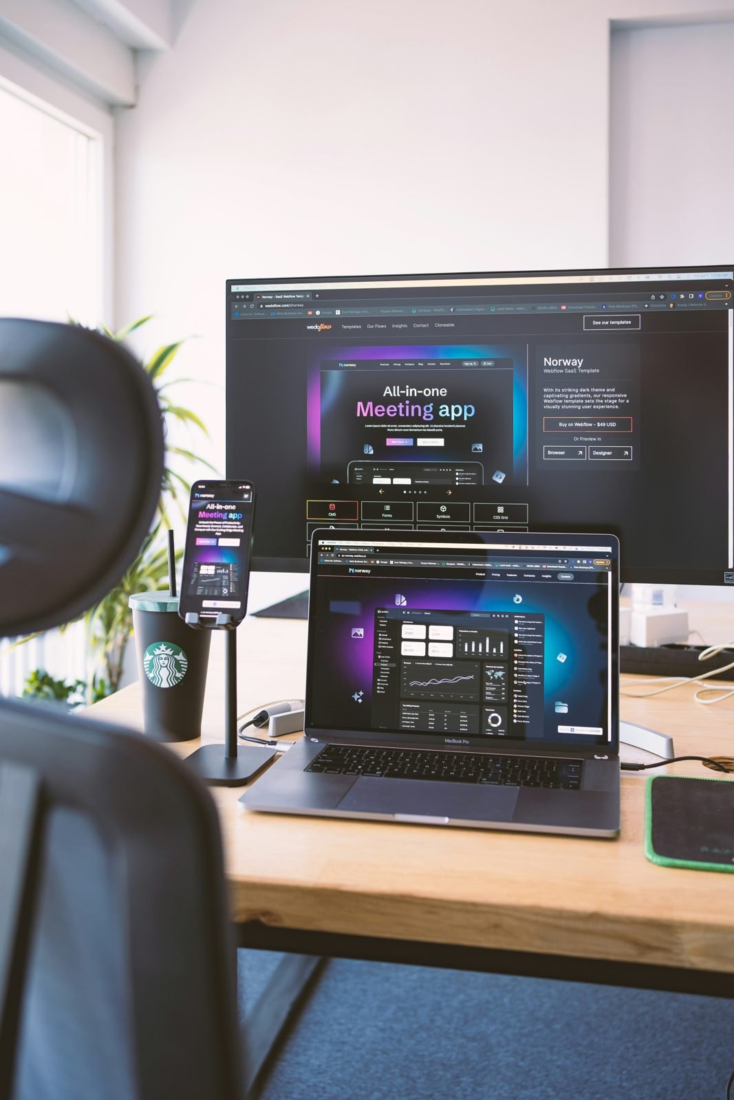 Dark themed SaaS website displayed across desktop, laptop and phone